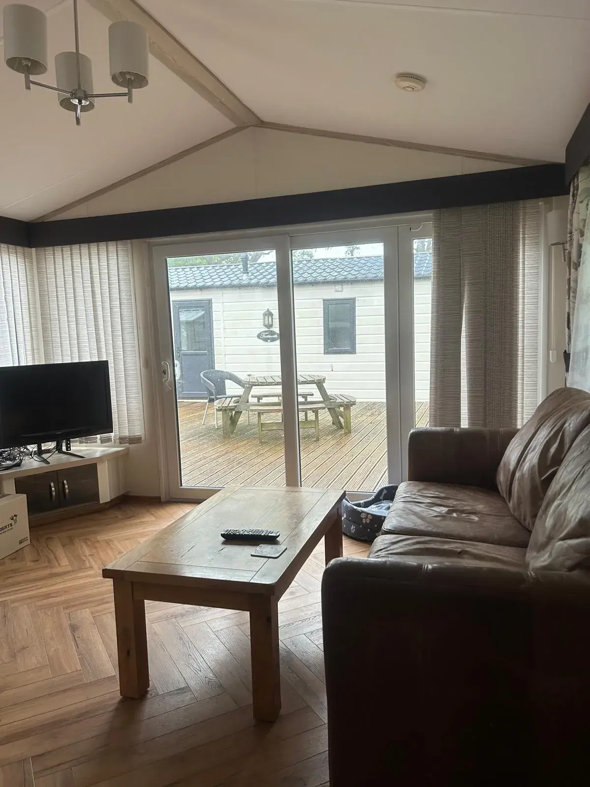 Open-plan lounge with sofa and patio doors onto the decking, Cornwall Lodge