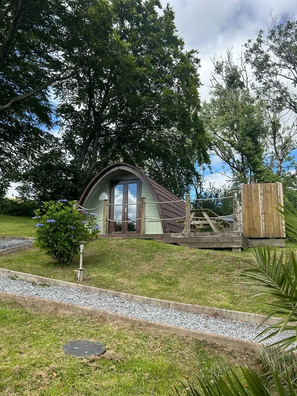 Jacuzzi Pod exterior on a bright day, surrounded by summer greenery