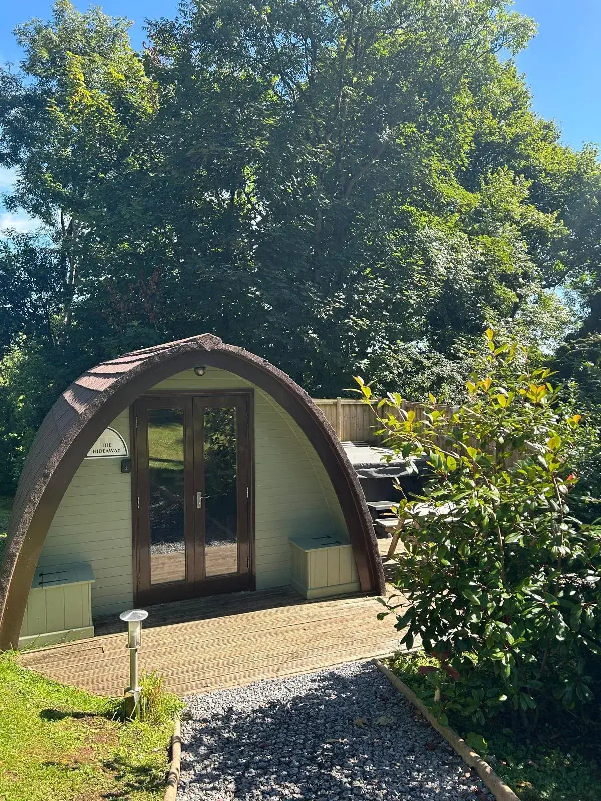 Hot Tub Pod exterior surrounded by trees, with the private hot tub visible on its own decking