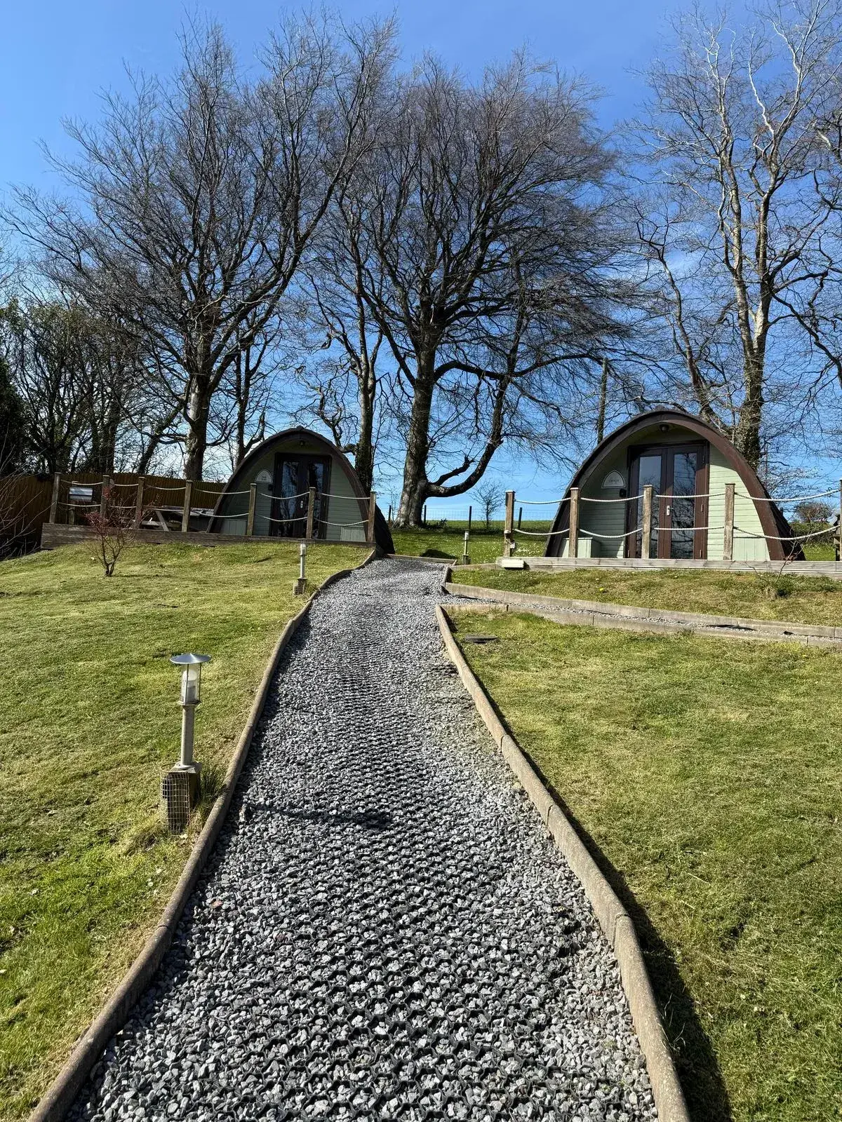 Two glamping pods reached by a winding gravel path on a crisp winter morning