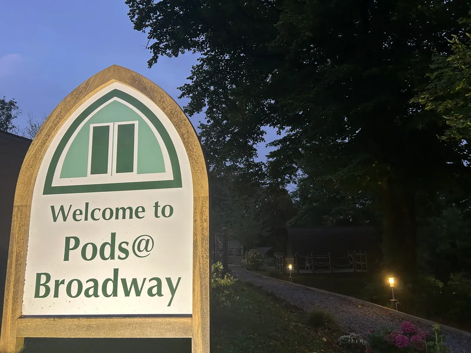Welcome sign glowing at dusk with illuminated pathway — magical arrival experience