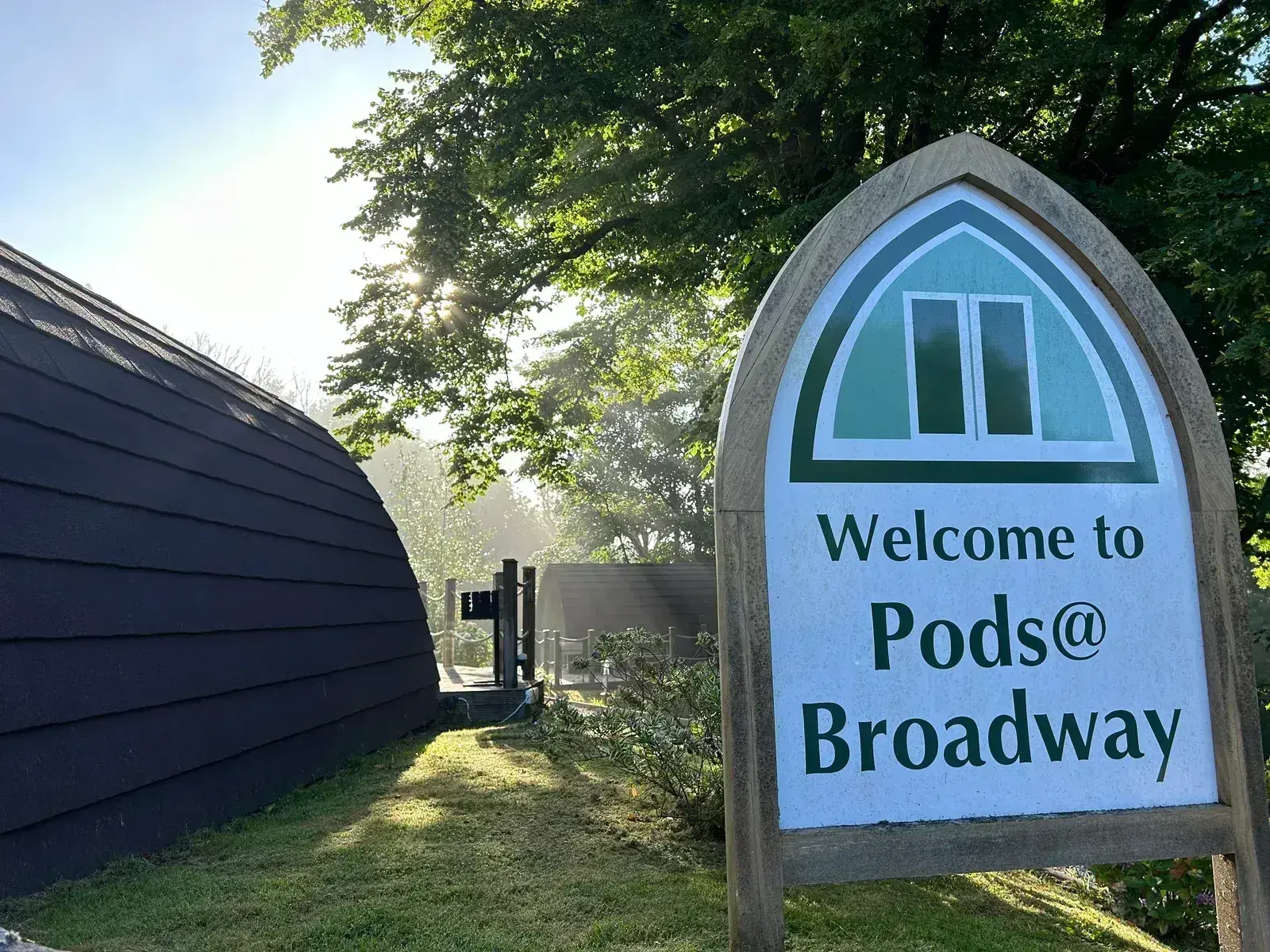 Welcome to Pods @ Broadway sign in morning mist — serene and atmospheric